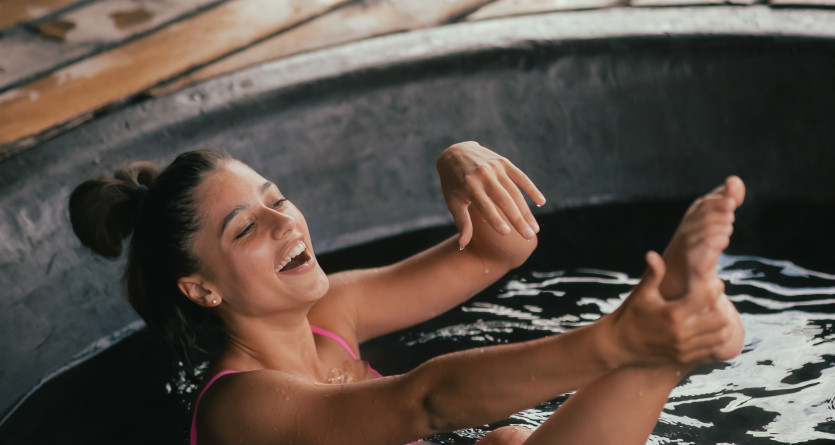 Femme souriante profitant d'un bain relaxant en plein air, rappel d'une "Love Room" &eacute;co-responsable.