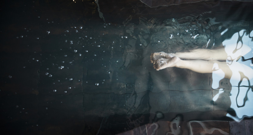 Femme &eacute;mergeant des eaux scintillantes d'un jacuzzi sombre et &eacute;l&eacute;gant