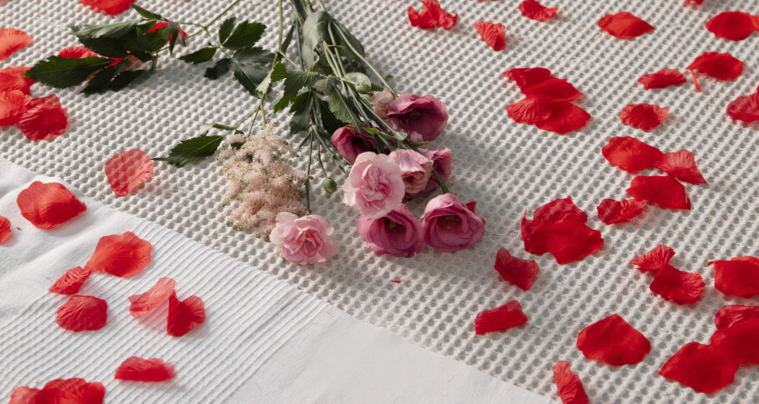 Lit d&eacute;cor&eacute; de p&eacute;tales de roses rouges et de bouquets pour une ambiance romantique