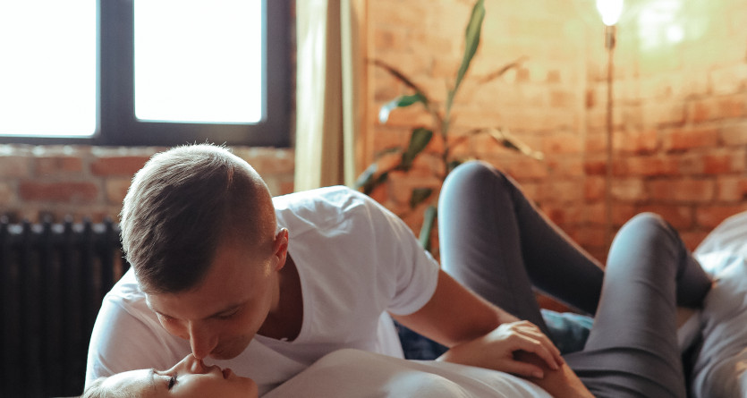 Couple s'embrassant tendrement sur un lit dans une chambre &agrave; la d&eacute;coration industrielle
