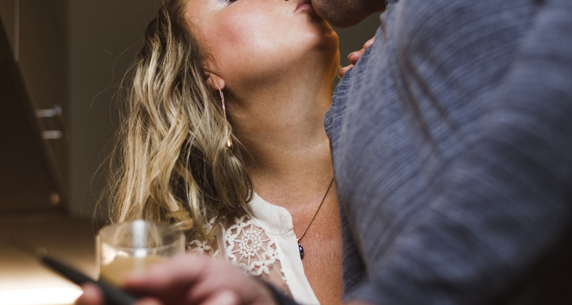 Couple partageant un baiser passionn&eacute; dans une ambiance intime avec un verre de vin
