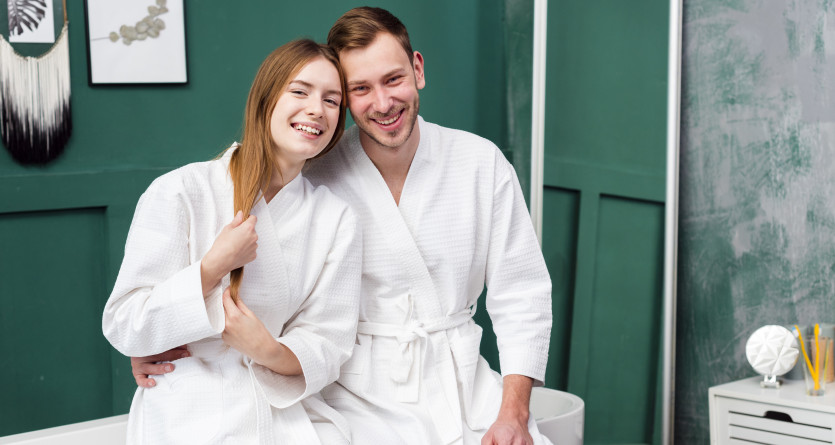 Couple souriant en peignoirs blancs dans un spa luxueux avec un d&eacute;cor &eacute;l&eacute;gant