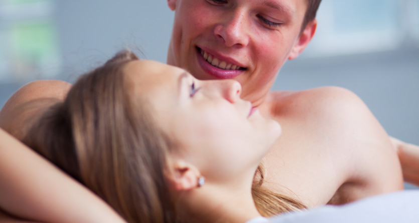 Jeune couple &eacute;changeant un regard amoureux dans leur lit douillet