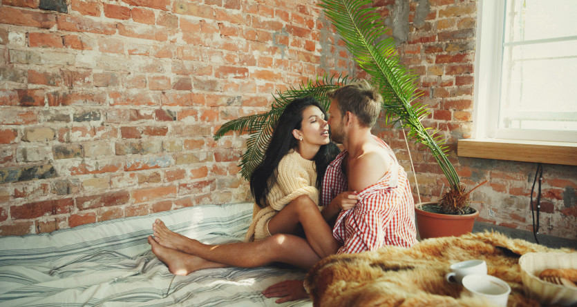 Couple enlac&eacute; sur un lit avec mur de briques expos&eacute;es, exprimant la tendresse