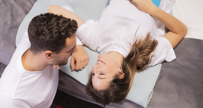 Couple d&eacute;tendu discutant sur un lit avec un livre