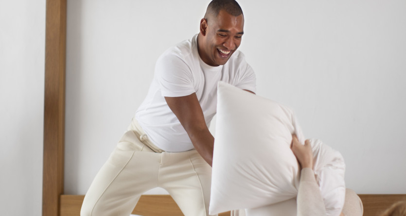 Couple en pleine bataille d'oreillers dans une chambre romantique