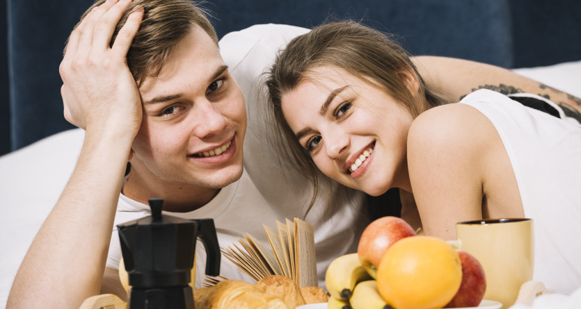 Couple souriant partageant un petit-d&eacute;jeuner romantique en Love Room