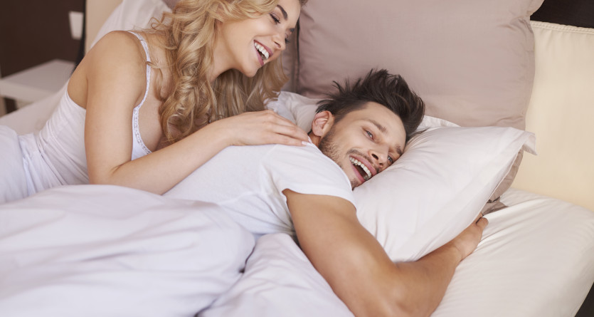 Couple se r&eacute;veillant joyeusement dans un lit