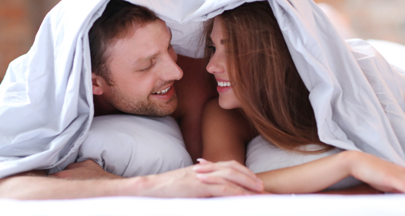 Couple partageant un moment intime sous les couvertures dans une love room