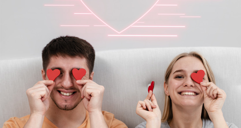 Couple souriant avec des c&oelig;urs dans une chambre romantique pour une escapade en couple