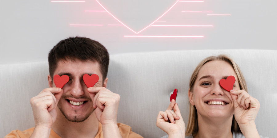 Couple souriant avec des c&oelig;urs dans une chambre romantique pour une escapade en couple