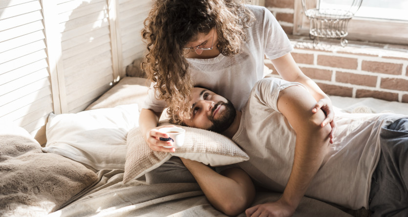 Couple allong&eacute; dans une chambre lumineuse partageant un moment de complicit&eacute;