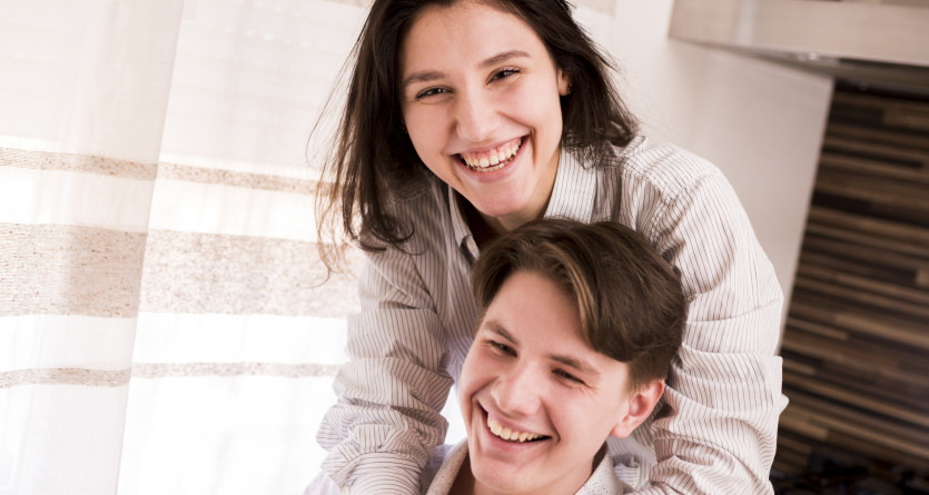 Couple joyeux partageant un moment complice dans une chambre lumineuse