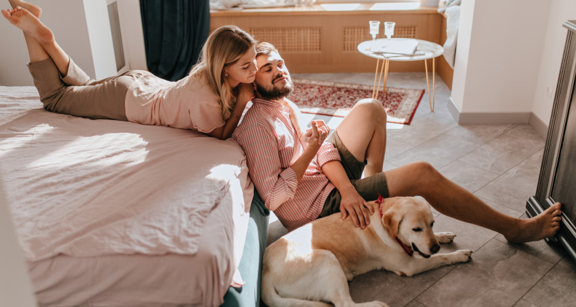 Couple dans une chambre ensoleill&eacute;e, avec leur chien, partageant un moment de d&eacute;tente