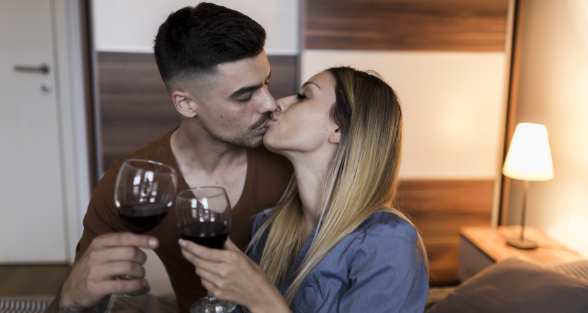 Couple s'embrassant et trinquant dans une chambre romantique