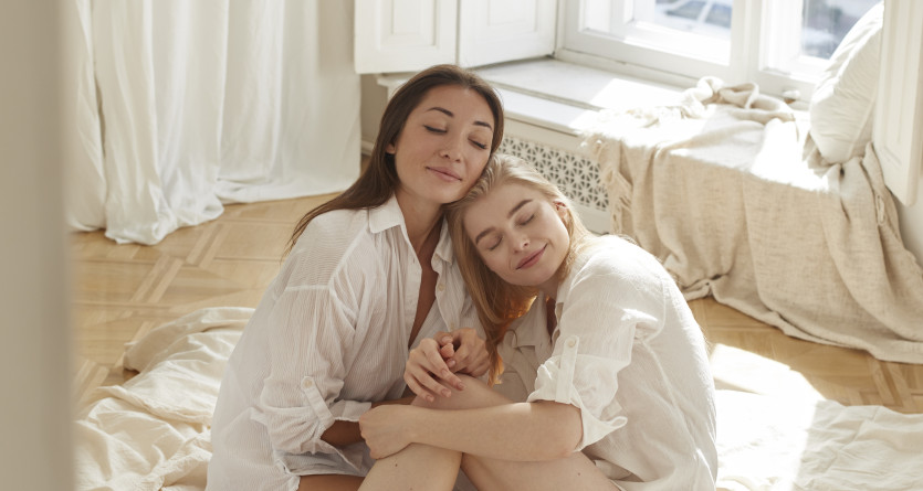 Deux amies assises ensemble dans une chambre lumineuse, partageant un moment de d&eacute;tente et de complicit&eacute;