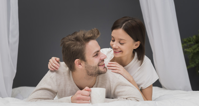 Couple souriant partageant un moment intime sur le lit