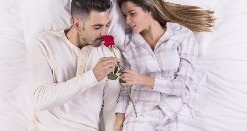 Couple allong&eacute; sur un lit, partageant un moment romantique avec une rose
