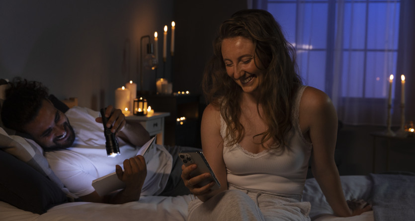 Couple s&rsquo;amusant dans une chambre romantique, entour&eacute; de bougies et de lumi&egrave;re douce